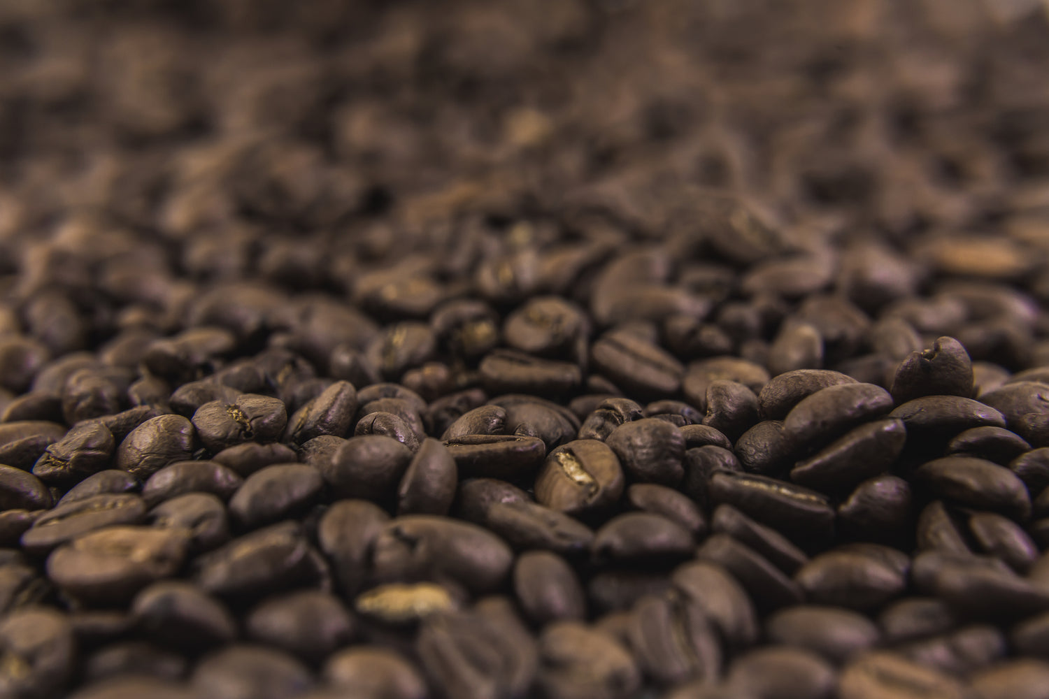 Et billede zoomet ind på hele kaffebønner i bunke 